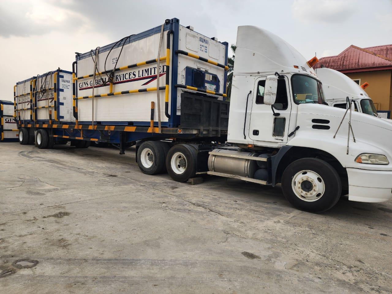 White Mack tractor unit hauling branded GGSL reefer containers on flatbed trailers