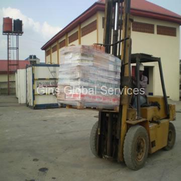 Forklift lifting palletised provisions past branded reefer containers at the yard